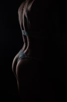 Bodyscape boudoir—rim-lit silhouette with dramatic shadow, fine-art curve.