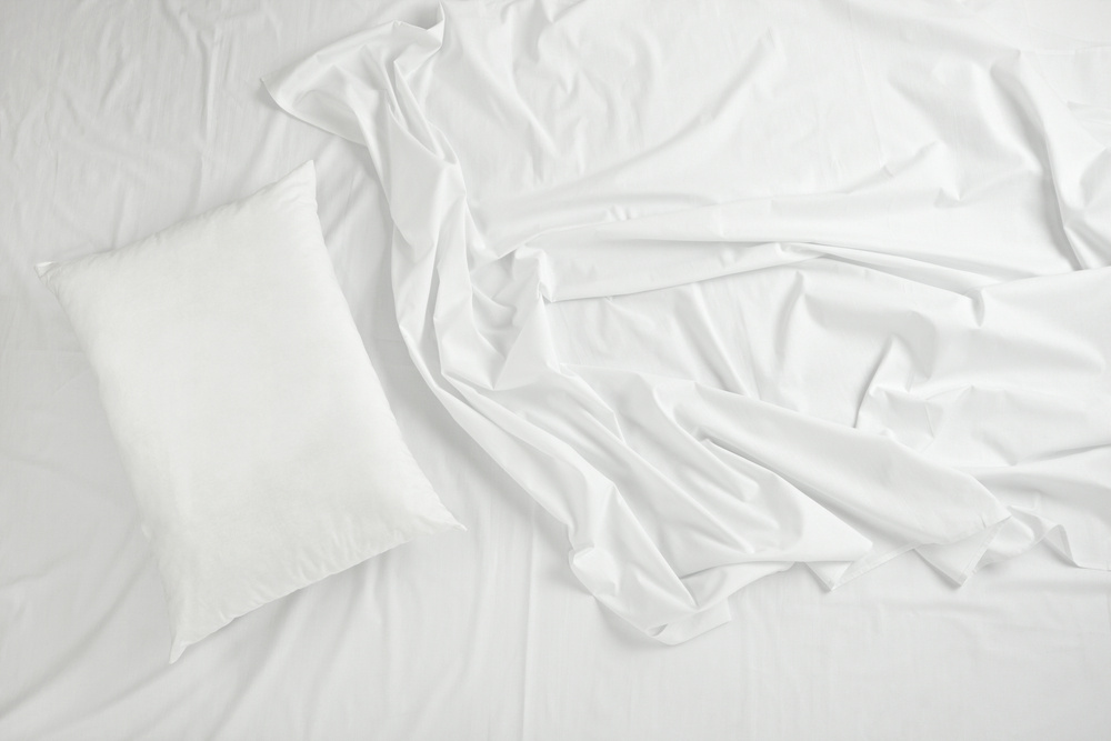 Cozy bed with soft white sheets and plush pillows, creating a serene and inviting atmosphere